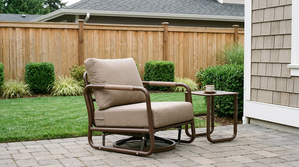 Bronze powder-coated aluminum patio armchair and matching side table on a paver terrace beside a cedar fence