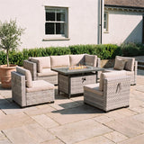 6-seat wicker patio set around a lit 55,000 BTU fire pit table at dusk