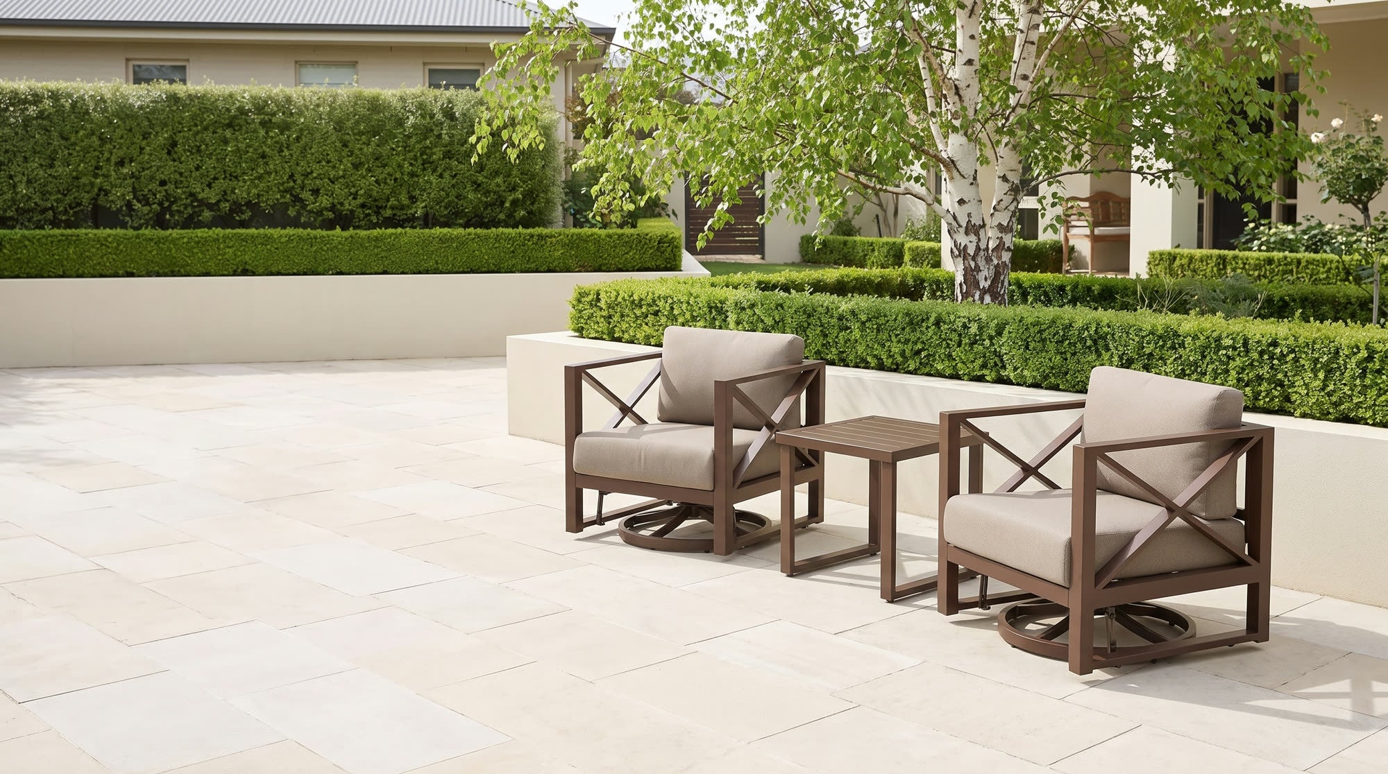 Two aluminum swivel lounge chairs and a side table on a stone patio