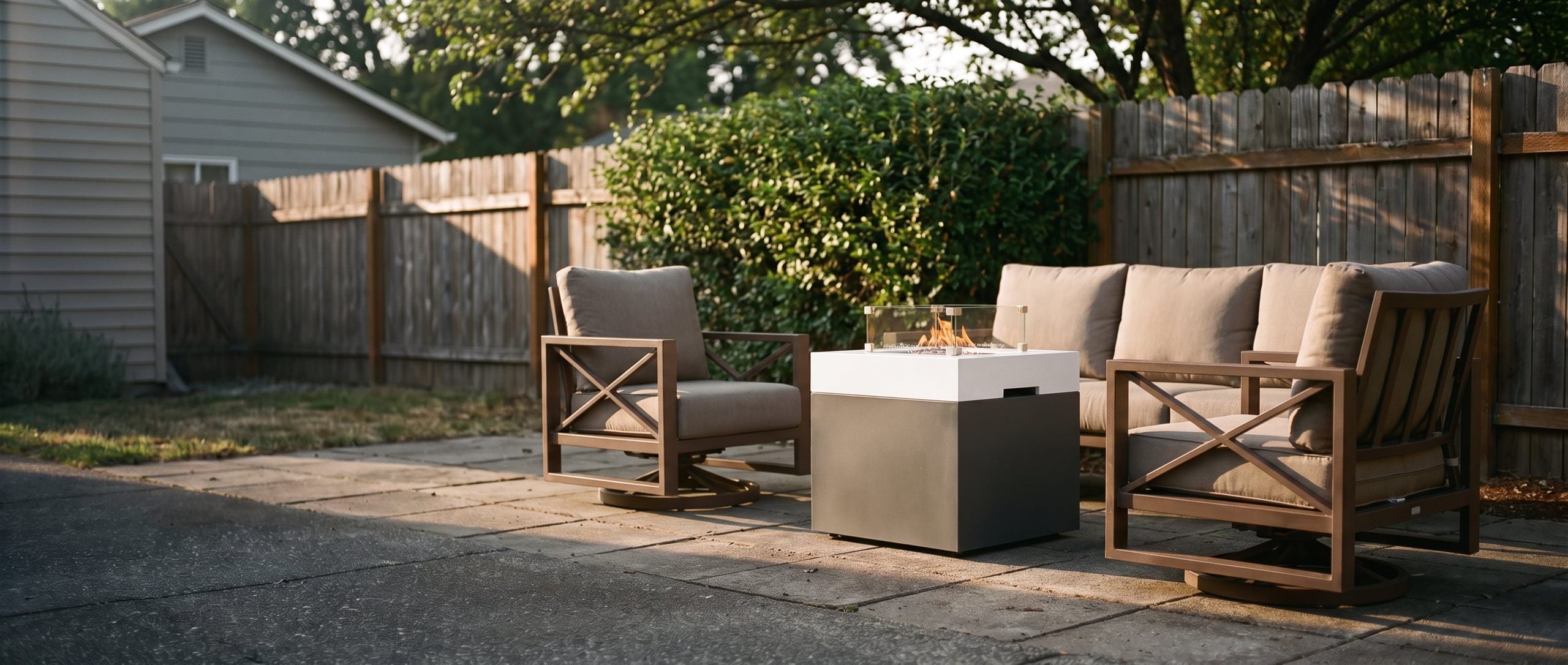 Bronze aluminum conversation set around a lit fire pit table on a backyard patio at golden hour